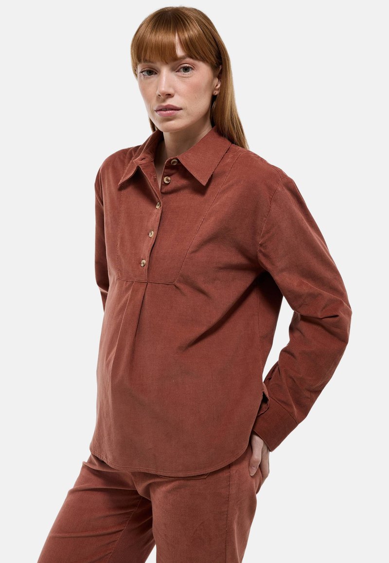 Chemise en velours côtelé marron à boutons avec col, dotée d'une patte de boutonnage à l'avant, de manches longues et d'une silhouette décontractée. Texture douce et coutures discrètes.