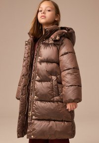 Brun puffjacka med huva, med quiltade sektioner, guldfärgade detaljer och sidofickor. Slätt, glänsande material med en avslappnad passform.
