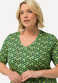 Top de manga corta con un patrón verde y acentos en azul y negro, diseño de escote en V y una textura de tela suave.