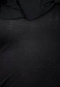 Svart tyg med en mjuk, fin stickad textur. Lätt skrynkligt, med en mjuk fall. Inga mönster eller detaljer synliga.