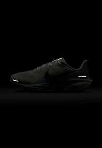 Chaussure de course Nike noire avec empeigne en mesh, lacets visibles et accents réfléchissants subtils au talon et aux orteils sur un fond sombre.