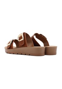 Sandales marron avec deux larges sangles et de grandes boucles métalliques. Semelle épaisse et texturée avec un léger talon.