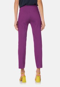 Pantalons violets ajustés avec un motif en losanges texturé, détenant une taille haute et des jambes fuselées, associés à des sandales à talons blocs jaunes.