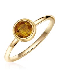 Kuldne sõrmus, millel on ümar, jahutatud kollane vääriskivi, mis on paigutatud siledasse beezli. Sõrmuse bänd on peen ja läikiv.