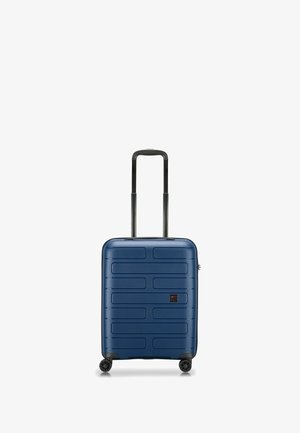 Valigia rigida di colore blu navy con forma rettangolare, superficie testurizzata caratterizzata da linee orizzontali, due ruote e maniglia retrattile.