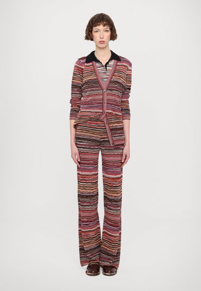 Completo lavorato a righe con colletto, maniche lunghe e pantaloni svasati in rosso, arancione e nero. Tessuto testurizzato e dettaglio di chiusura con bottoni laterali.