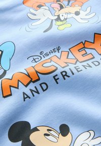 Svetlomodrá látka s kreslenými grafikami postáv Disney, vrátane Mickeyho Mouse a Goofyho, s odvážnym oranžovým textom "Mickey a priatelia."