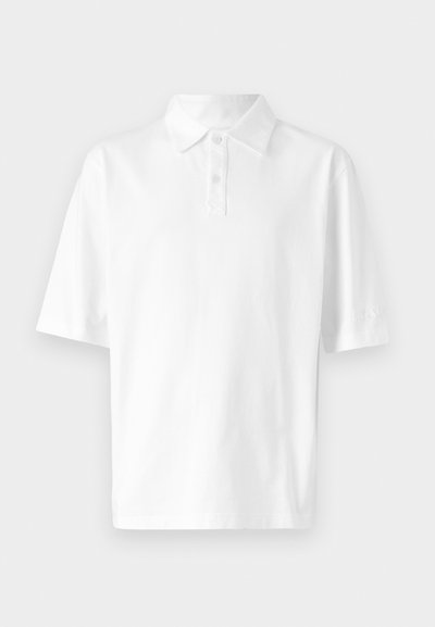 White polo shirt made of cotton, featuring a two-button placket, short sleeves, and a subtle logo on the sleeve. Smooth texture.