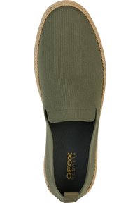Zapatilla slip-on verde de malla con tela texturizada, paneles laterales elásticos y suela envuelta en yute. Presenta una plantilla negra con marca en dorado.