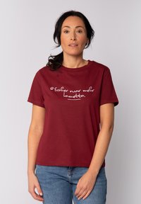Bordeaux-farbenes Baumwoll-T-Shirt mit kurzen Ärmeln und Rundhalsausschnitt, das in lässiger Schriftart weißen Text trägt mit der Aufschrift: "Früher war mehr Lametta."