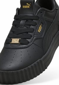 Schwarze Ledersneaker mit strukturiertem Obermaterial, runder Zehenpartie, flachen Schnürsenkeln, goldenen Logoakzenten und dicker, geriffelter Sohle. Perforierte Details an der Seite.