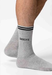 Graue gerippte Socken mit schwarzen Streifen am Bund und der Aufschrift "SNOCKS" in Schwarz. Hergestellt aus einem weichen Material, das für Komfort sorgt.