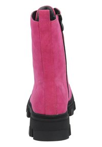 Botín de ante rosa con suela de goma negra y cremallera trasera. Presenta un tacón alto y un acabado texturizado en el material superior.