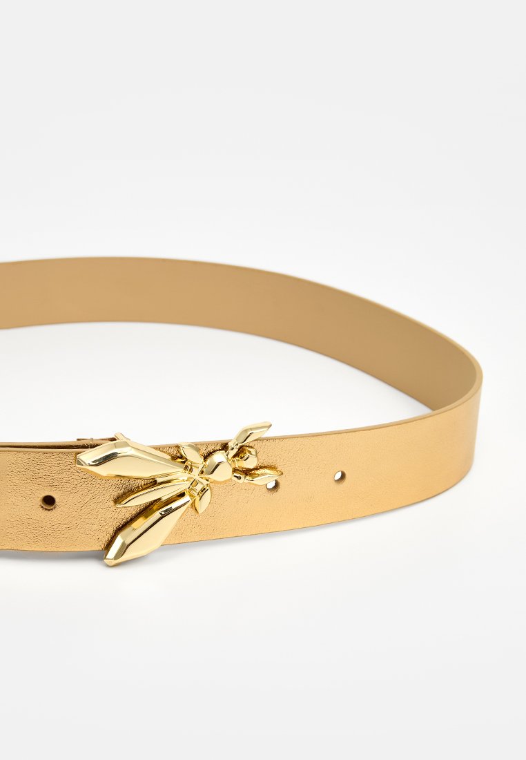 Cintura in ecopelle color sabbia con una fibbia a forma di insetto dorato, caratterizzata da una superficie liscia e diversi fori di regolazione per la vestibilità.