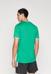 Πράσινο κοντομάνικο μπλουζάκι με στρογγυλή λαιμόκοψη και λευκή επένδυση. Το υλικό είναι απαλό και ελαφρύ, κατάλληλο για αθλητική χρήση.