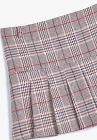 Geweven geruite rok in crème, rood en marineblauw. Heeft plooien en een textuurstof, met een ruitpatroon over de hele rok.