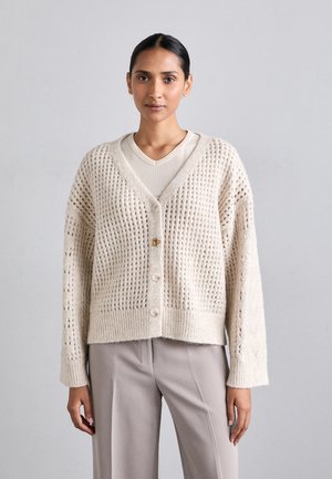 Beige knitted cardigan with a loose fit, featuring a V-neck, long sleeves, and textured open weave, fastened with large buttons.