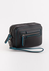 Mini monedero de cuero negro compacto con ribete en azul verdoso, bolsillo con cremallera en la parte frontal, compartimento principal con cremallera y correa de muñeca adjunta sobre fondo blanco.