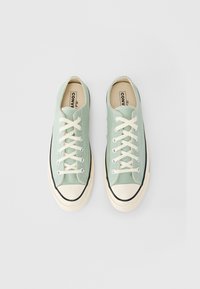 Πράσινα πάνινα παπούτσια με μπεζ κορδόνια, λαστιχένιο κάλυμμα μπροστινού μέρους και μαύρη επένδυση. Διαθέτουν επίπεδη σόλα και υφασμένη επιφάνεια.