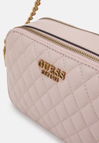 Borsa in pelle sintetica rosa trapuntata con zip dorata e logo del marchio. Presenta una tracolla a catena e una forma rettangolare.