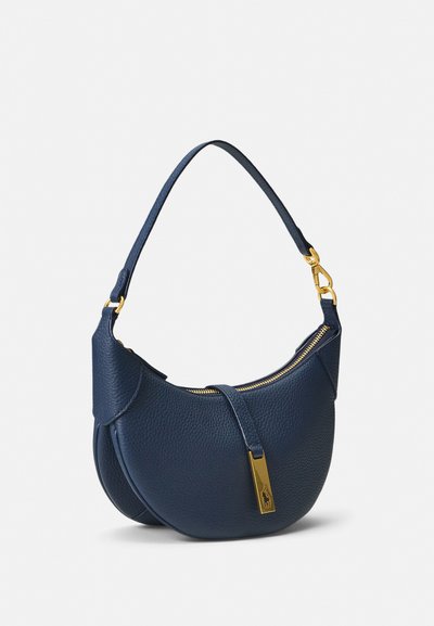 Tummansininen nahkainen olkalaukku, jossa on kaareva muoto, kultainen vetoketju ja korostustagi. Pinnassa on kivimäinen tekstuuri.