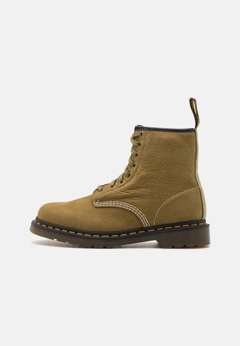 Bottine à lacets en cuir tan avec semelle noire, surpiqûres jaunes et languette de tirage sur fond blanc, vue de côté extérieur.