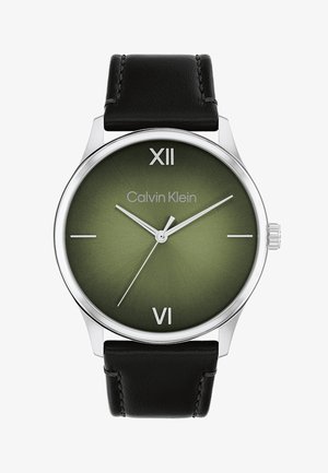 Calvin Kleini kell, millel on ümmargune hõbedane korpus, roheline gradientdials, must nahkrihm, rooma numbrid XII ja VI ning hõbedased käed.