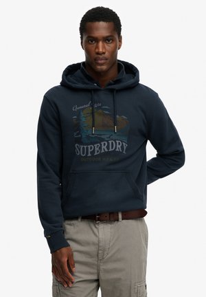 Granatowa bluza z kapturem z nadrukiem z przodu przedstawiającym góry i wodę, kaptur ze sznurkiem oraz kieszeń kangurka. Miękka tekstura tkaniny.