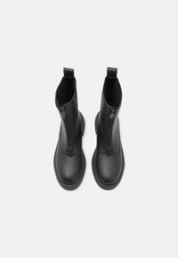 Stivaletti neri con esterno in pelle liscia, pannelli laterali elasticizzati e zip frontale. Punta rotonda e suola piatta in gomma.