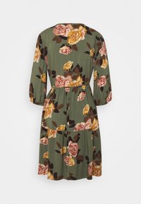 Abito floreale con maniche lunghe, caratterizzato da una base di tessuto verde, grandi motivi di rose in rosa e giallo, e un design con vita arricciata.