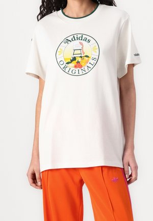 Bílé bavlněné tričko s kulatým potiskem ovoce a nápisem „Adidas ORIGINALS“ v zelené barvě. Výstřih je orámován zeleným lemováním.