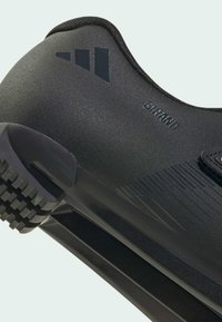 Zapato de ciclismo negro con textura suave, diseño elegante, suela de goma con estrías y logo en el lateral. Material ligero.