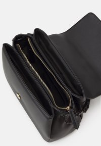 Black leather handbag with three compartments, gold zipper accents, smooth texture, and a flap top closure. Interior lined with fabric.