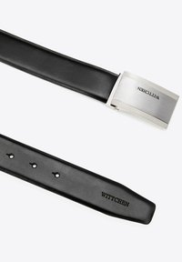 Zwarte leren riem met een rechthoekige zilveren metalen gesp. De gesp heeft een gestructureerd oppervlak en een reliëflogo "WITTCHEN." Vijf verstelgaten.