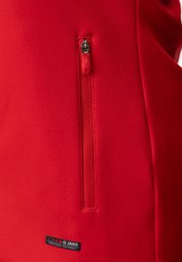 Rote sportliche Jacke mit einer kleinen Reißverschlusstasche auf der linken Seite, aus glattem Stoff. Logotag unten links.