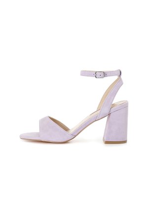 Sandalo in suede lilla con tacco, punta aperta, cinturino alla caviglia e tacco a blocco spesso per maggiore stabilità. Texture liscia e design minimalista.