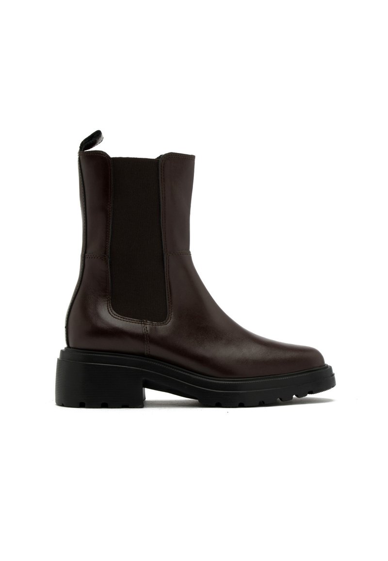 Brązowy skórzany botek za kostkę z elastycznymi panelami bocznymi, okrągłym noskiem i masywną gumową podeszwą. Posiada pętelkę z tyłu dla ułatwienia zakładania.