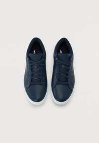 Baskets en cuir bleu marine avec des bouts ronds, des lacets plats et des semelles en caoutchouc de couleur claire. Texture lisse et design minimaliste.