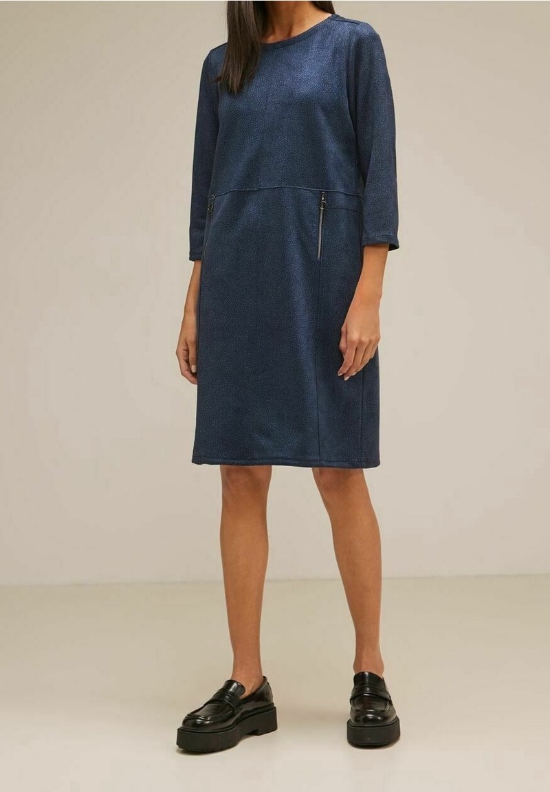 Mörkblå klänning med trekvartsärmar och rak siluett. Har två fickor med dragkedja och en texturerad tyg.