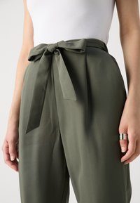 Olivgrüne hoch taillierte Hosen mit einem breiten Gürtel und Schleifendetail, aus weichem Stoff gefertigt, mit lockerer Passform und subtiler Ausstrahlung.