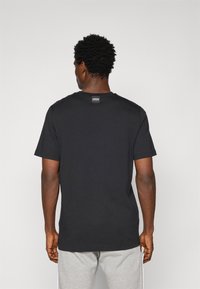 Sort bomulds t-shirt med klassisk rund halsudskæring og korte ærmer. Har et lille logo mærke bag på halsen. Subtil tekstur.
