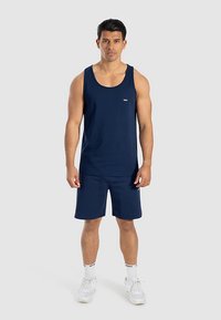 Granatowy tank top i pasujące krótkie spodenki wykonane z lekkiego materiału. Posiadają okrągły dekolt i małe logo na piersi.