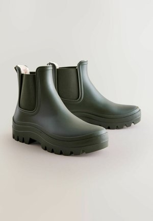 Grüne Gummistiefel mit dicken, strukturierten Sohlen und elastischen Seitenpanelen, ausgestattet mit einem weichen Innenfutter und einem abgerundeten Zehenbereich.