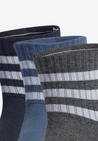 Drie paar sokken: donkerblauw, blauw en grijs, met witte strepen. Het materiaal lijkt ribbelig en zacht, ontworpen voor comfort.