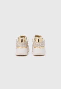 Beige mønstrede sneakers med gulddetalje på hælen, hvid sål og blød tekstur. Har en rund form og polstret bagside.