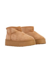 Courtes bottines en suède camel avec un bout rond, un côté élastique et une semelle en caoutchouc épaisse et texturée. Présentent un design minimaliste.