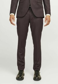 Ciemne burgundowe spodnie garniturowe o gładkiej fakturze, slim fit, z szlufkami na pasek, zestawione z czarnymi sznurowanymi butami.