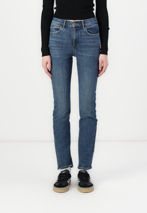 Blue denim jeans with a straight-leg fit, five pockets, a button closure, and subtle faded detailing. Paired with black sneakers.