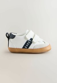 Scarpe per bambini bianche e blu navy con due cinturini in Velcro, suola in gomma marrone e un anello sul tallone per una facile calzata. Presentano il marchio "BAKER" sul lato.