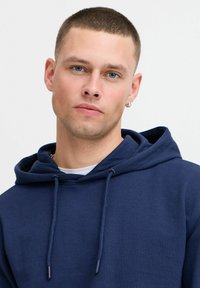 Navy blue hooded sweatshirt made of cotton blend fabric. Features a drawstring, ribbed cuffs, and a soft texture.
